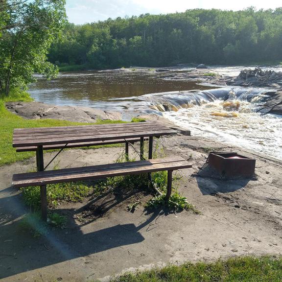 Picnic table and fire pit beside Whitemouth Falls