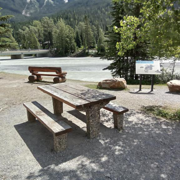 Picnic table and bench on the edge of the Kicking Horse River in Field